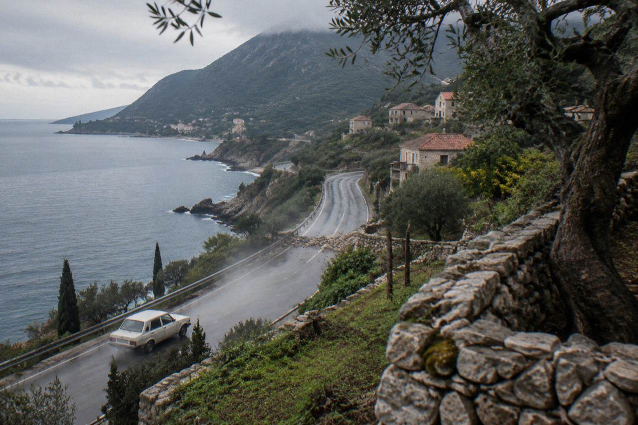 Coastal road winding along the Adriatic shoreline toward green hills