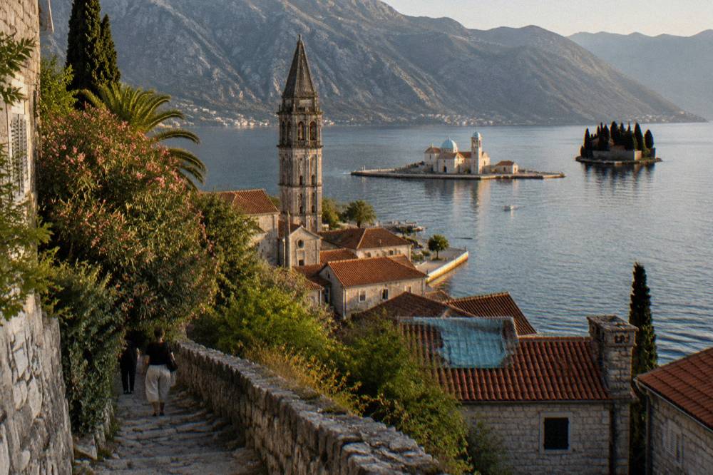 Small baroque town of Perast at the foot of hills with two islands in calm water