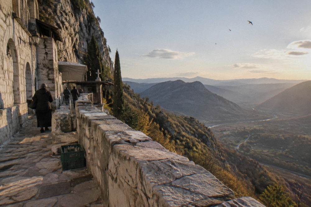 Valley and hills seen from a monastery terrace with pale stone walls in the foreground