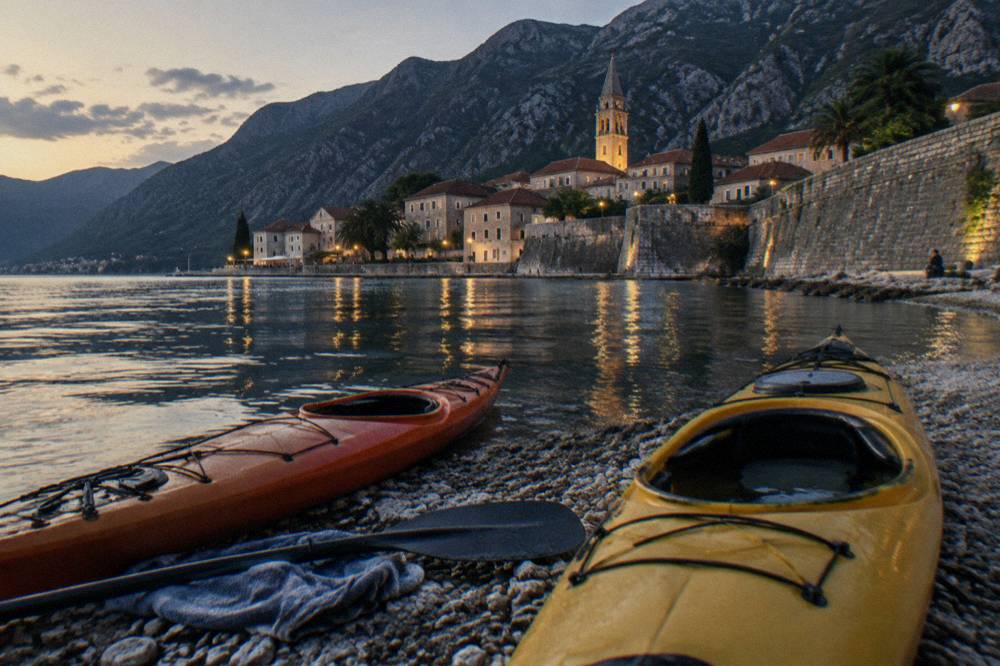 Kayaks pulled onto a rocky shore beside clear shallow water in a bay cove