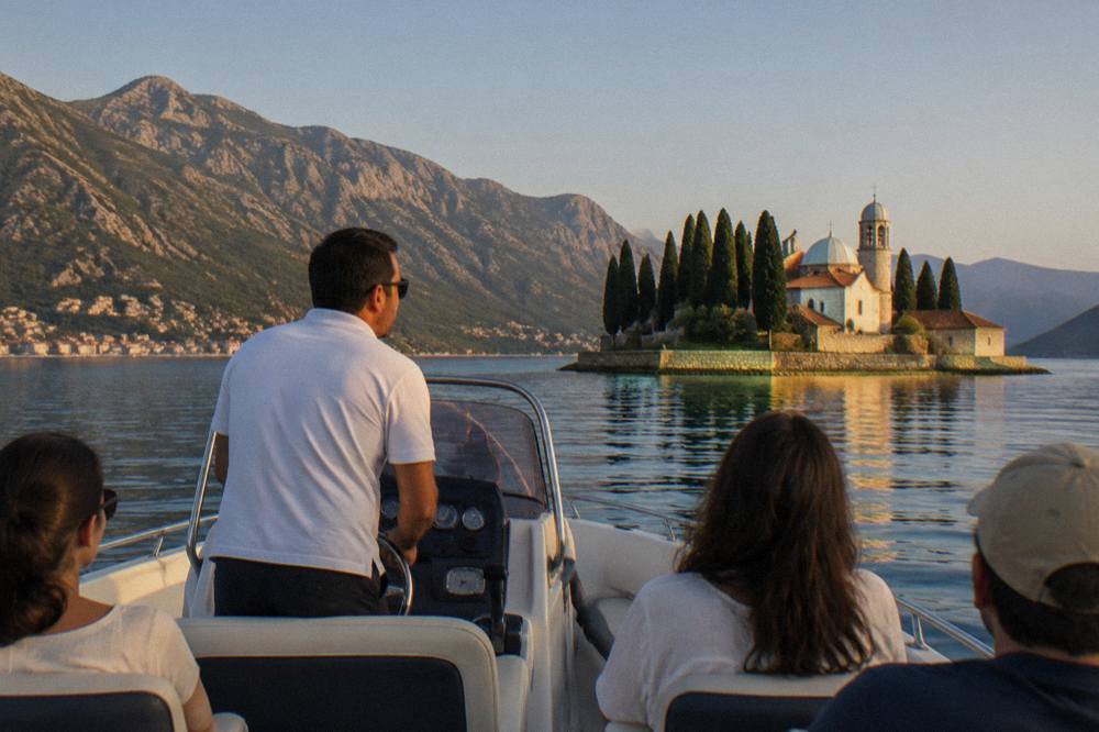A speedboat guide speaking to passengers seated along the sides of the boat on calm blue water