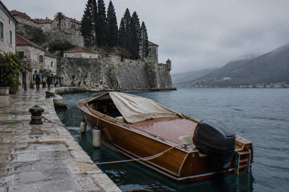 A wooden speedboat moored beside a stone quay in a Mediterranean harbour