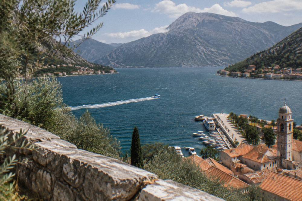 A bright blue speedboat cutting across a wide bay toward distant mountains