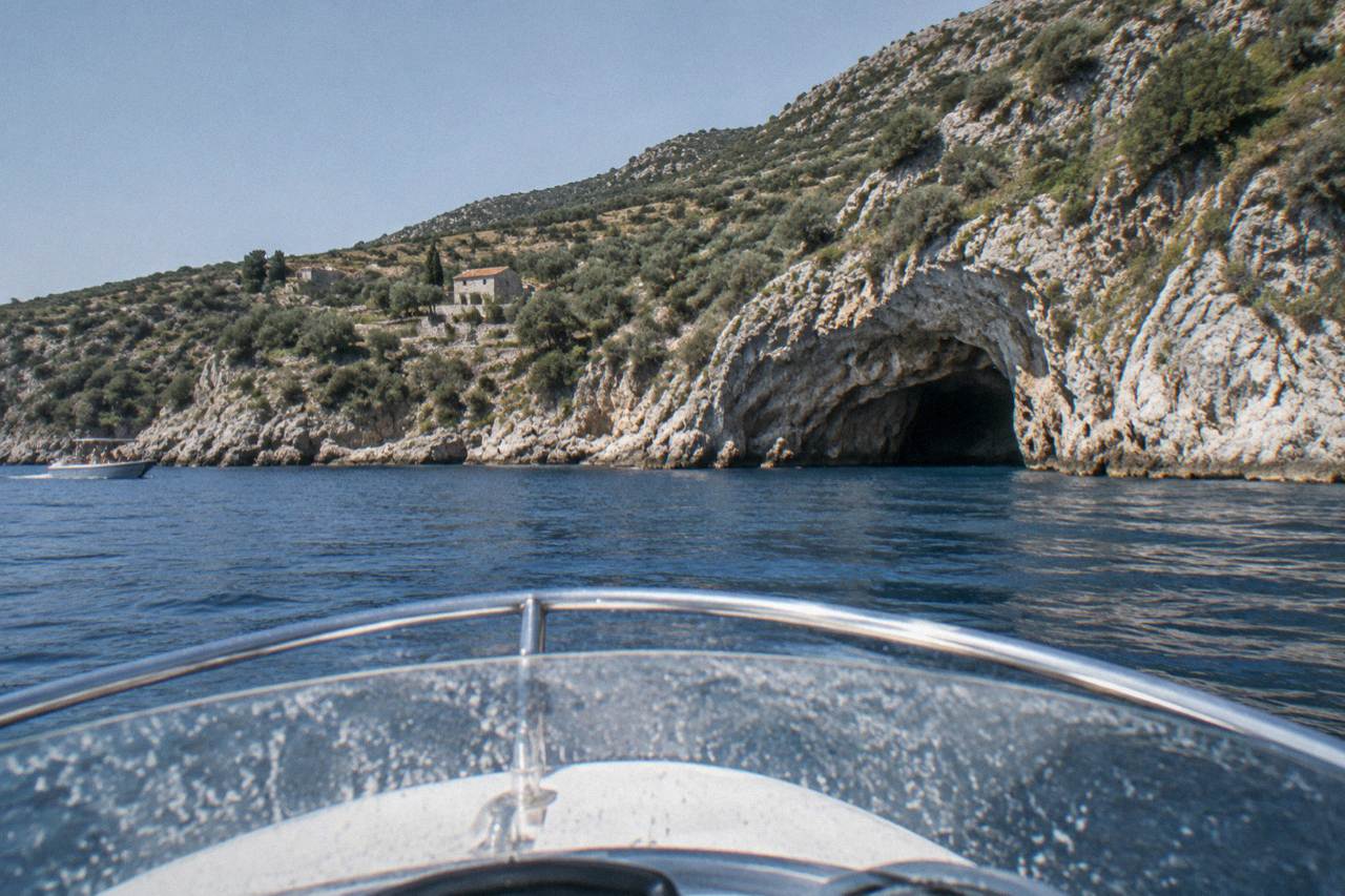 A speedboat crossing open water toward a rocky coastline on a calm morning