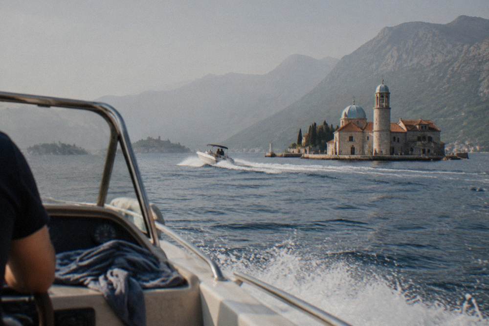A speedboat cutting across the open water of a mountain-ringed Adriatic bay