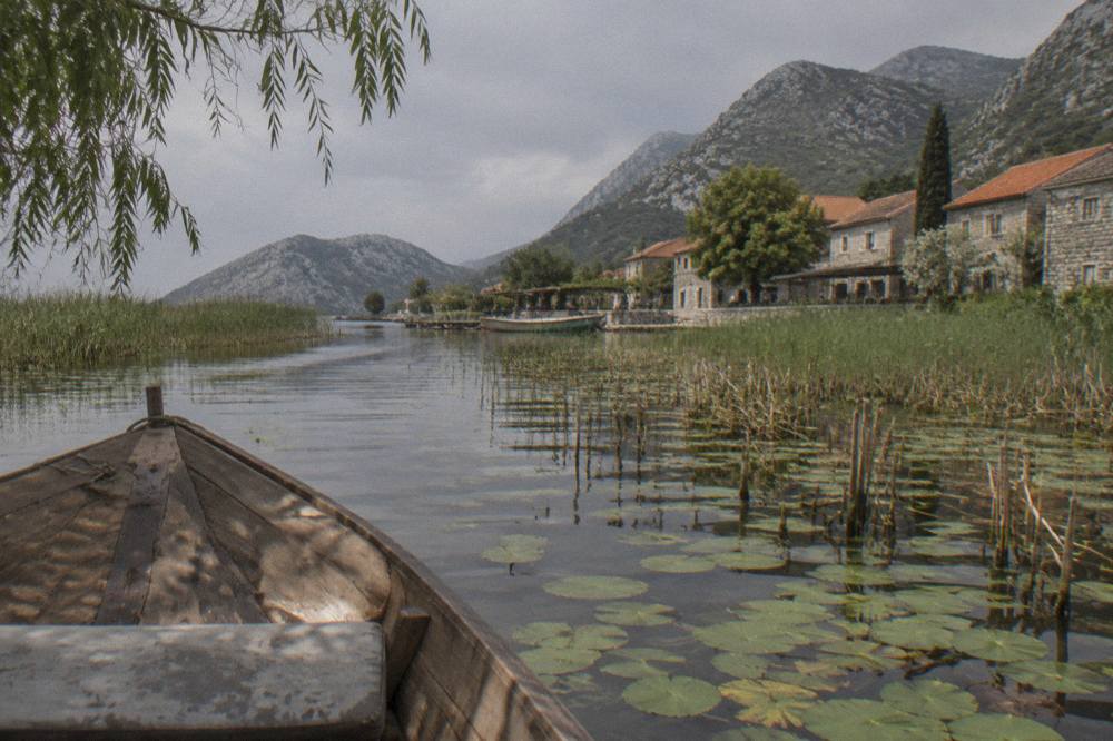 Traditional wooden boat cruising through narrow reed channels on a calm lake