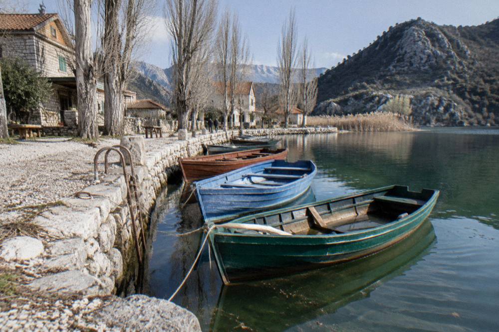Fleet of small boats moored along a stone waterfront village at the edge of a lake