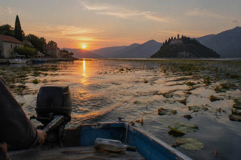 Wide lake view at golden hour with a distant monastery headland and calm water