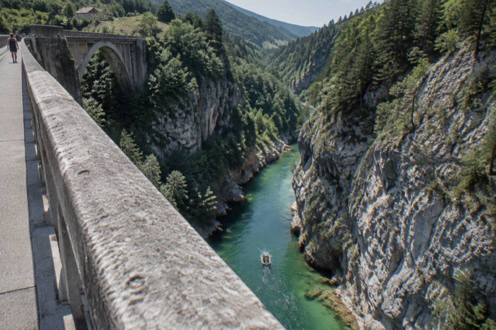 Inflatable raft carrying paddlers through a narrow green section of a river canyon