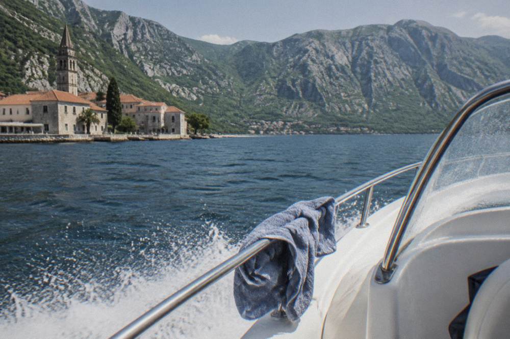 Speedboat crossing open bay water toward rocky coastline under a clear sky