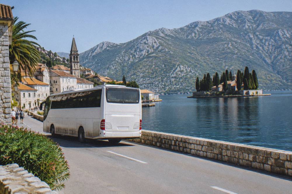 Tour coach parked at a roadside stop with hills and sea in the distance