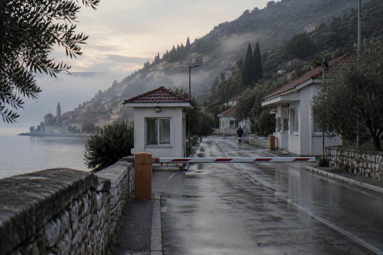 Quiet border checkpoint buildings on a coastal road between green hills