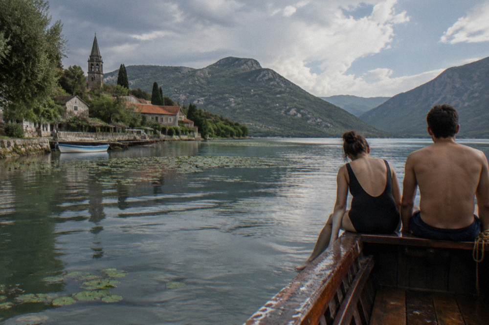 Wooden boat moored at a swim stop on Lake Skadar with passengers preparing to enter the water