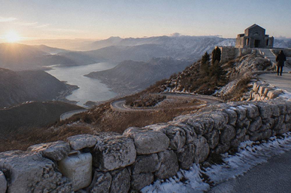 A tight hairpin bend on a stone mountain road above the Bay of Kotor with the bay visible far below