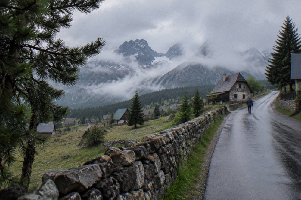 Mountain road winding toward a high plateau with distant limestone peaks