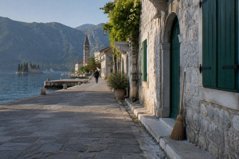 Stone palaces with arched facades standing along the quiet waterfront street in Perast