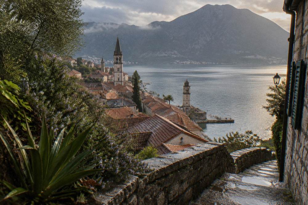 Mountains dropping steeply to the bay with a small town and church towers at the shoreline