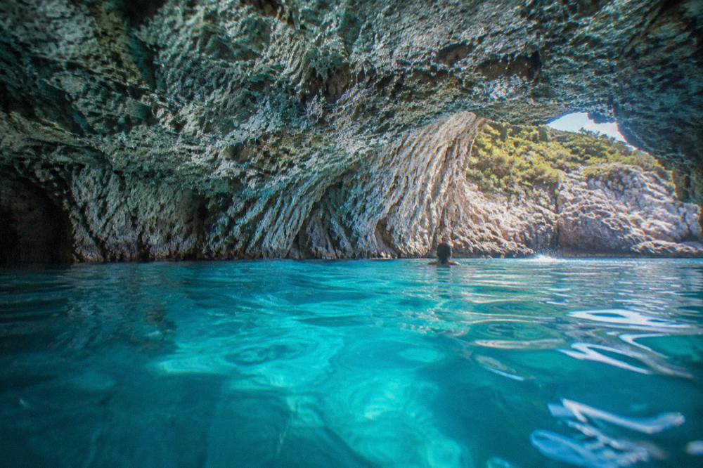 Turquoise water glowing inside a sea cave with light streaming through an underwater opening
