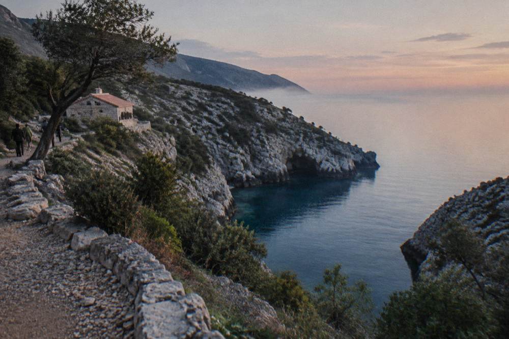 A calm blue sea along a rocky peninsula in early morning light with no boats