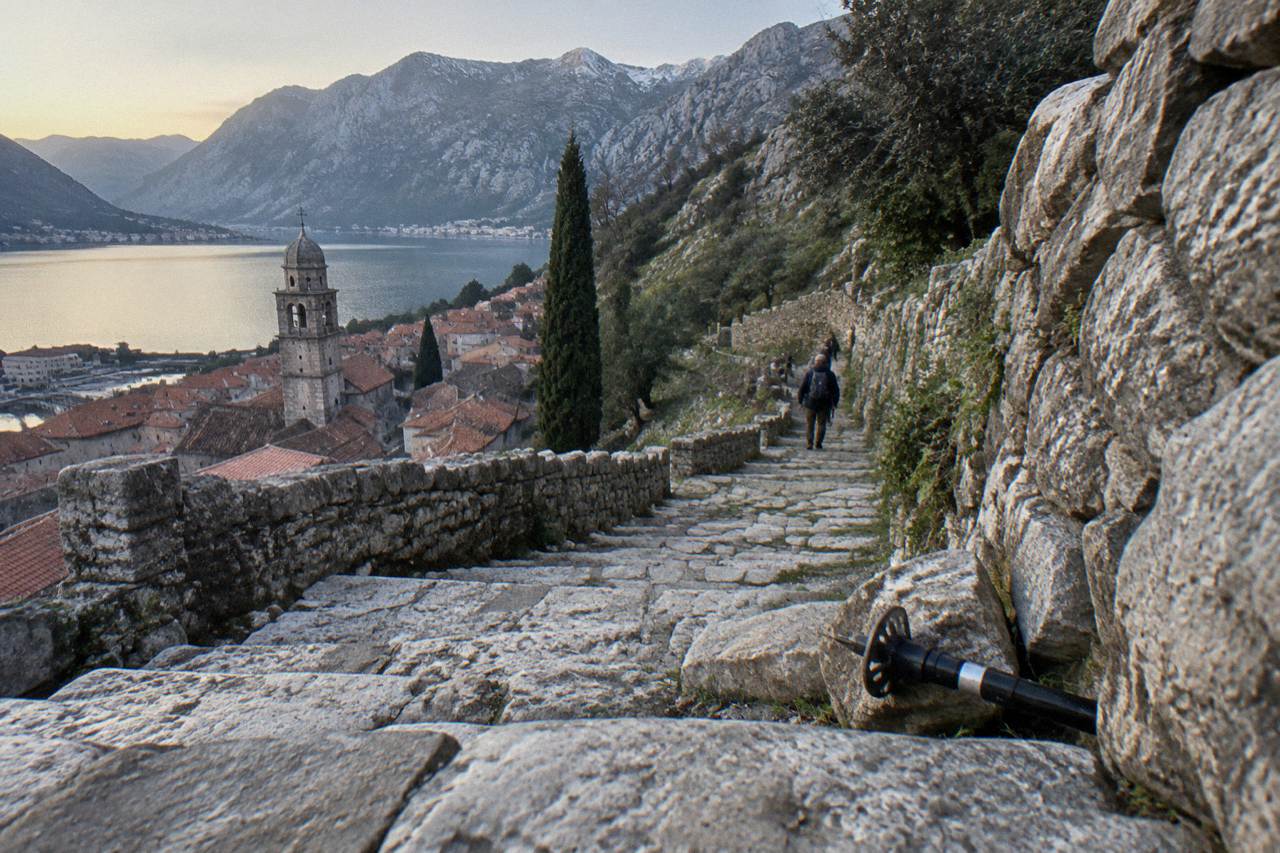 Stone switchback trail climbing the mountainside above the terracotta roofs of Kotor Old Town