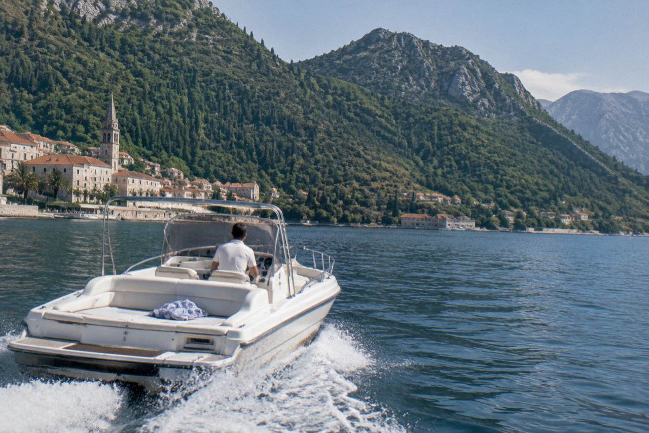 Speedboat crossing the blue water of the Bay of Kotor toward wooded hills