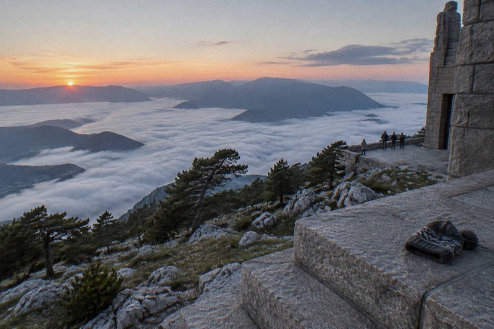 Stone mausoleum on a mountain summit above low clouds