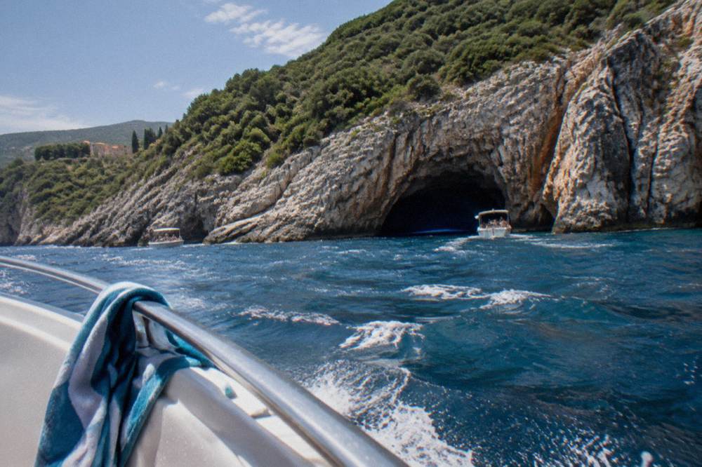 Speedboat crossing open blue sea toward a rocky coastline