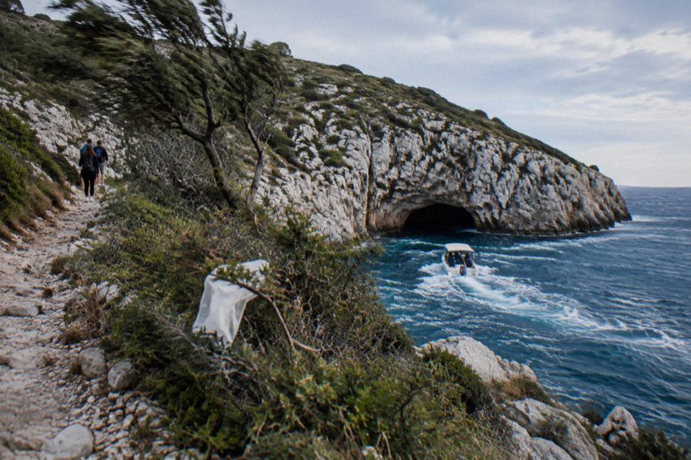 Speedboat crossing open blue water toward a rocky cave entrance in a coastline