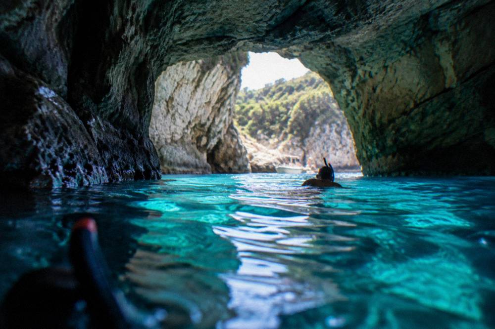Turquoise water glowing inside a sea cave with a dark rock ceiling
