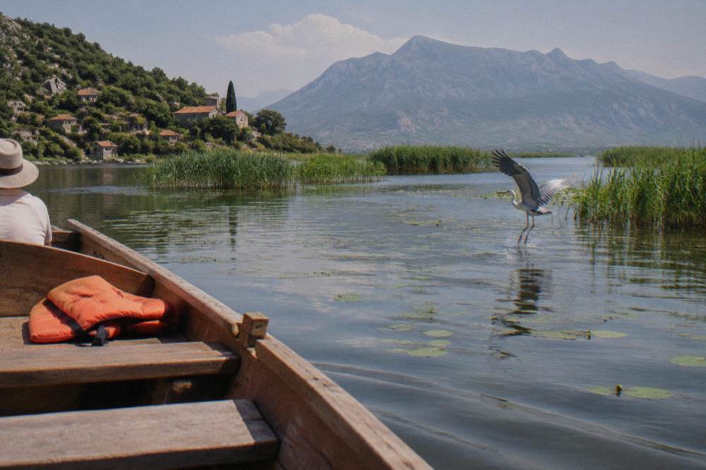 Wooden boat on a wide lake with reed beds and hazy mountains on the horizon