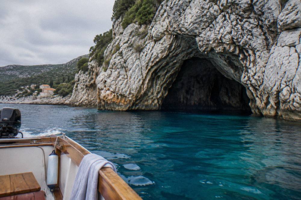 Clear turquoise water at the mouth of a sea cave with a small boat waiting outside
