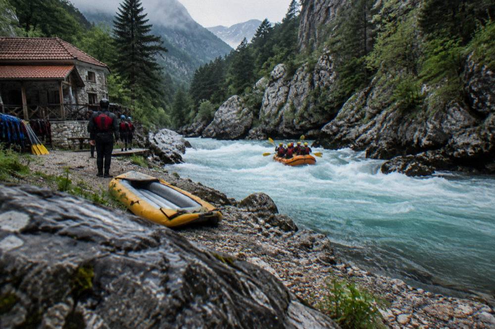 River running between steep forested canyon walls with a raft on the water