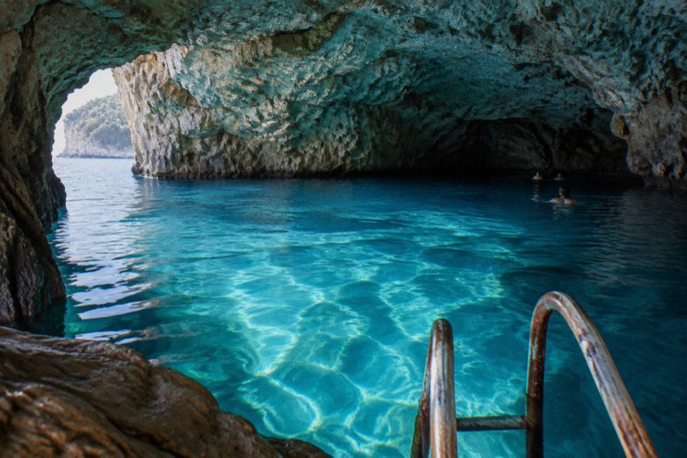 Turquoise water glowing inside a wide sea cave lit by morning sunlight
