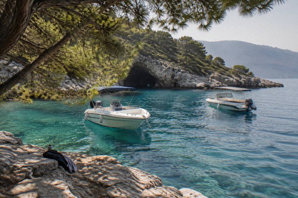 Anchored speedboats bobbing on calm turquoise water beside a rocky coastline