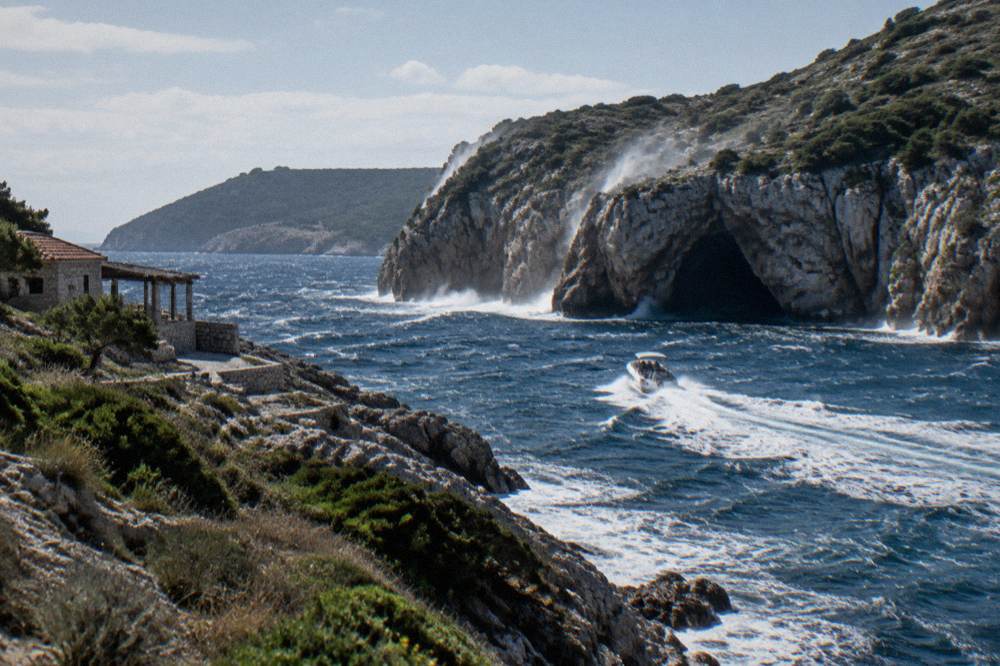 A speedboat cutting across open blue water toward rocky cliffs on the outer coast