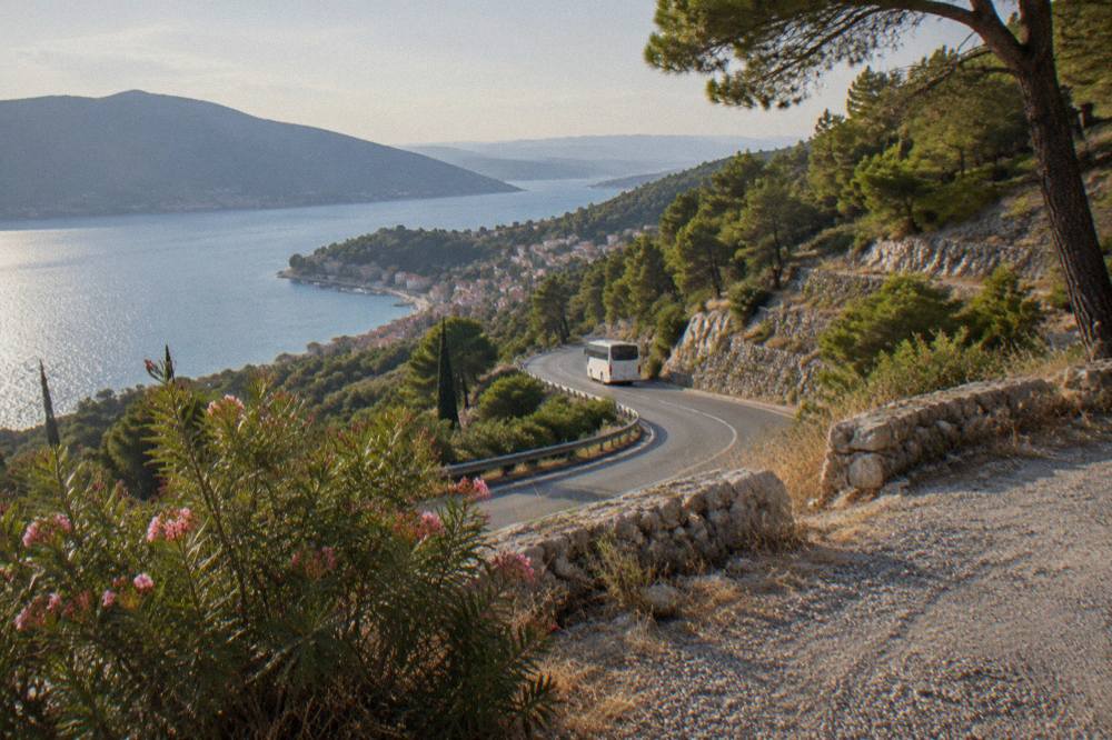 Coastal road winding along the Adriatic shoreline toward Montenegro with dry hills
