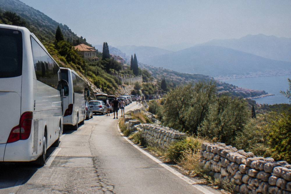 Buses and cars queued at a border checkpoint building in summer daylight