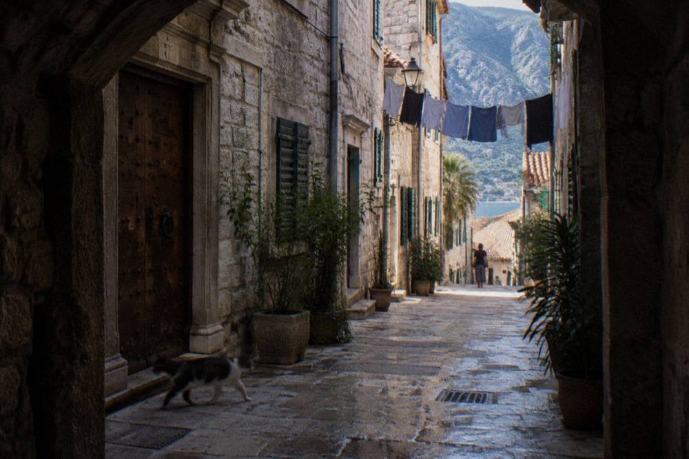 Narrow stone lane in Kotor Old Town with old wooden doors and hanging laundry