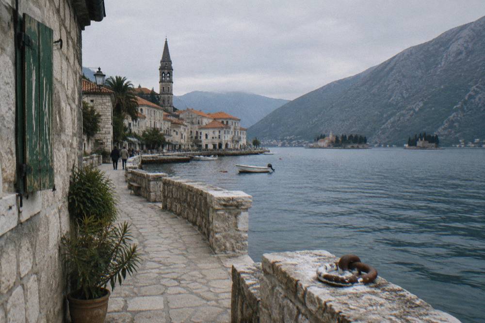 Waterfront promenade of Perast with baroque facades and two small islands in the bay