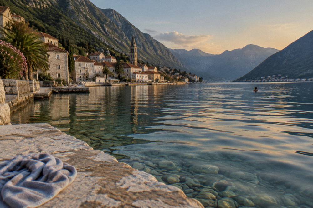 Stone swimming ledge on the Bay of Kotor with clear water and hills behind