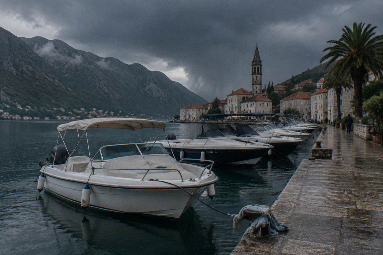 Speedboats moored on calm water beside the stone walls of Kotor old town