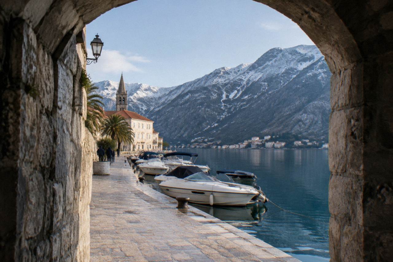 Speedboats moored at a stone quay on the Bay of Kotor with hills in the background