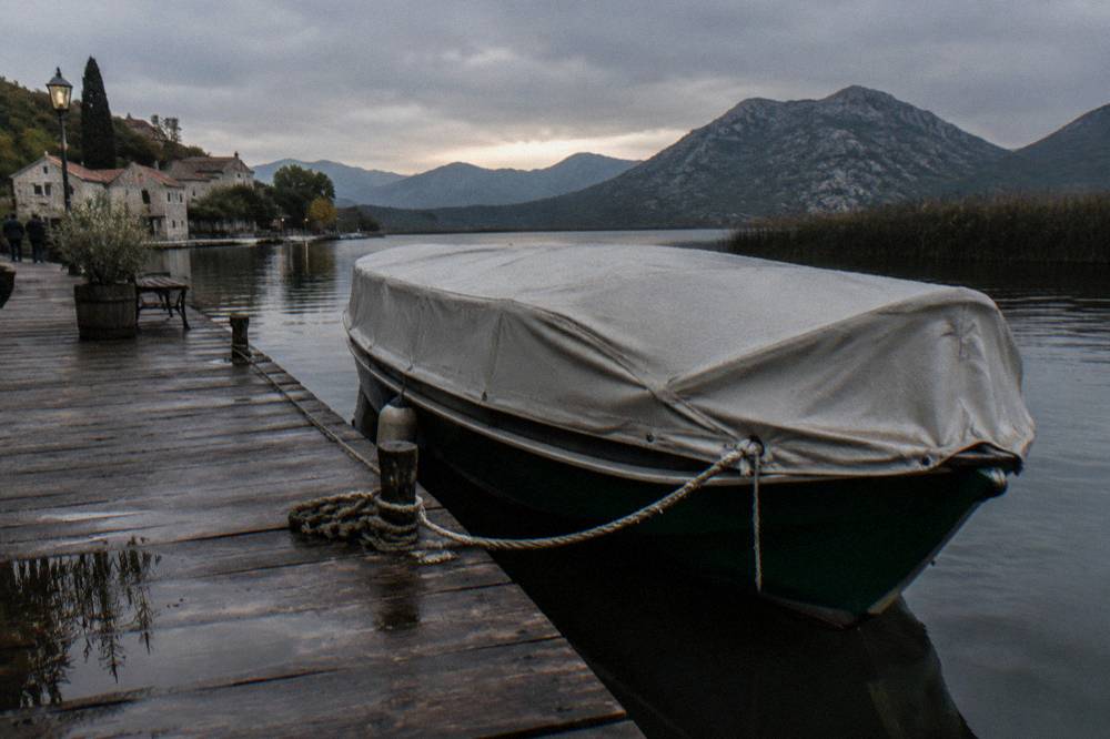 Traditional wooden boat with a canopy moored at a wooden jetty on a calm lake