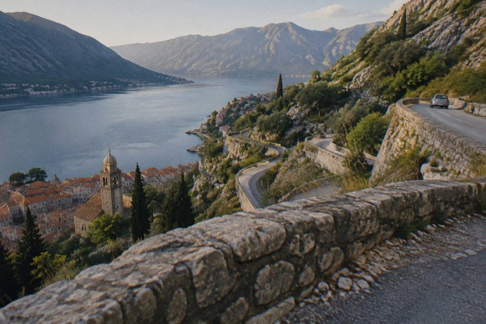 Mountain road with hairpin bends descending toward the Bay of Kotor in clear weather