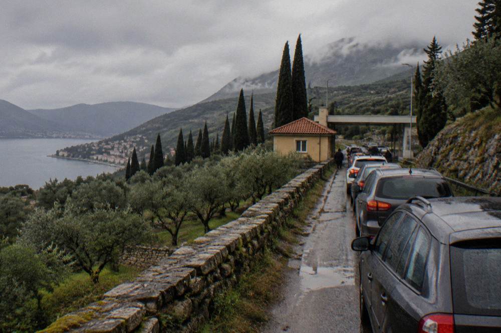 Queue of cars waiting at a small border checkpoint building between green hills