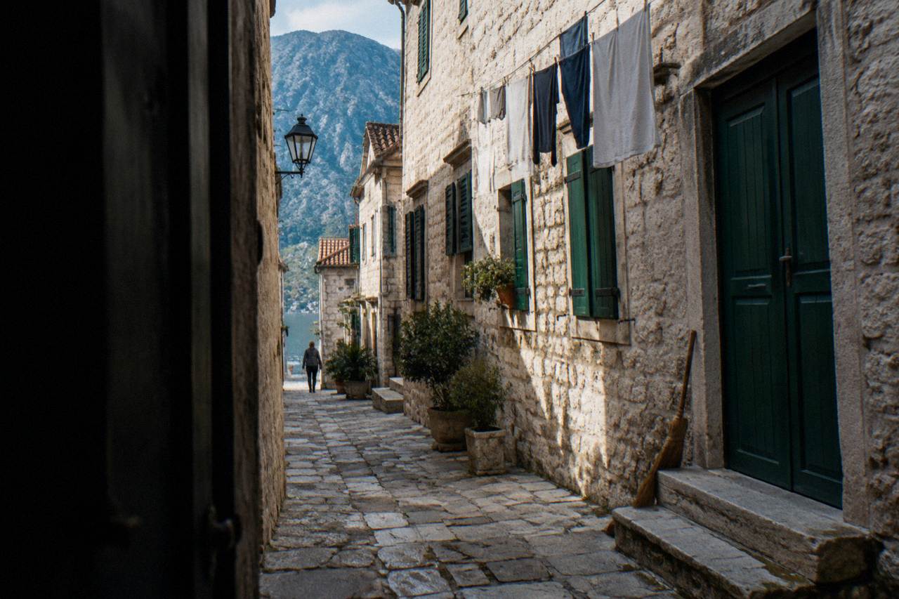 Quiet stone street in Kotor old town with closed shutters and morning light on the walls