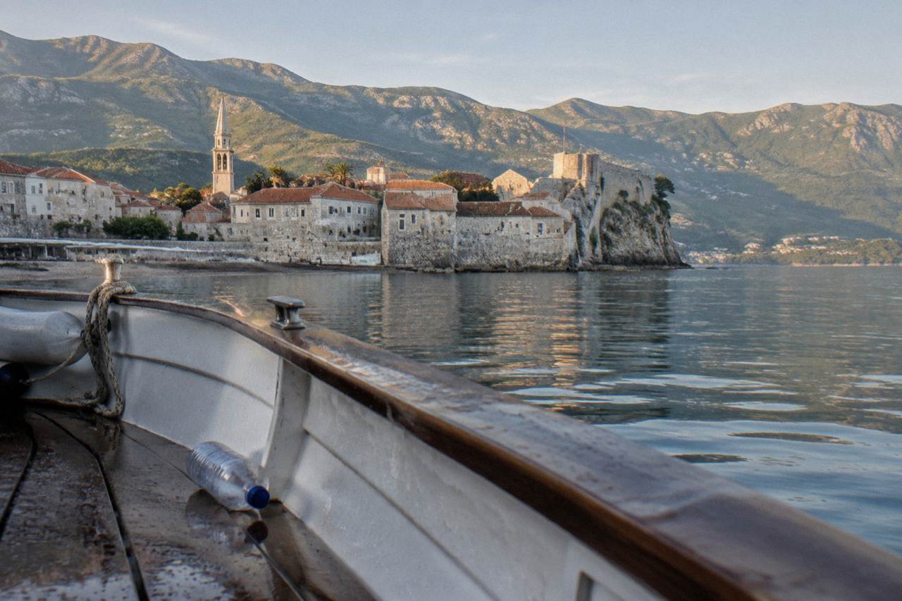 Terracotta rooftops of an Adriatic old town rising toward green mountains across a calm bay