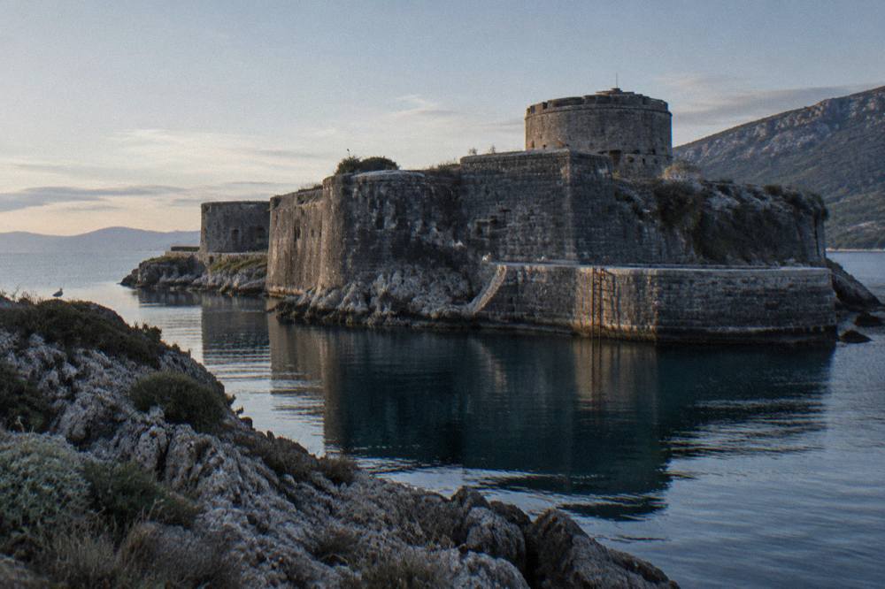 Mamula Island fortress with high stone walls and a tower rising from the sea