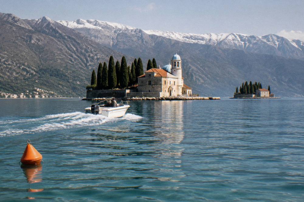 Speedboat crossing calm turquoise water in the Bay of Kotor near stone islands