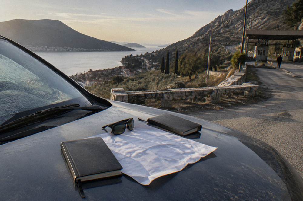 A parked car with a map and travel documents laid out on the hood